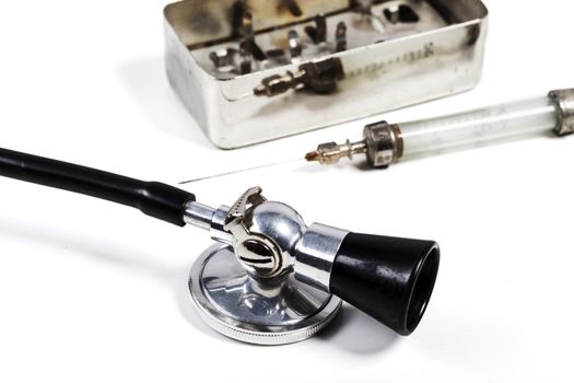 Old Glass Syringe with needle and black stethoscpe isolated on white background