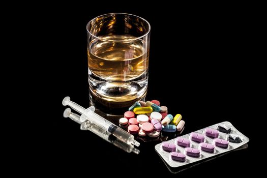 Medicine and alcohol isolated on black background with reflection