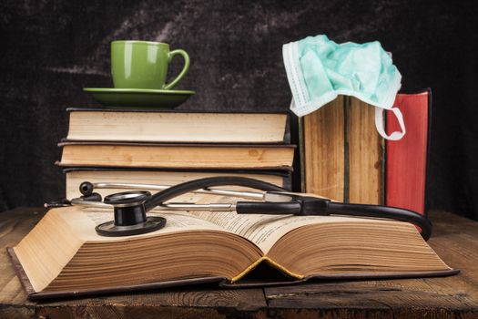 Stethoscope on open book and coffee on books pile