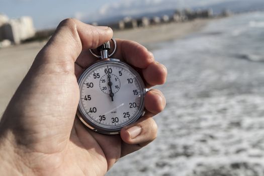 analog Stopwatch in hand with sea in the background