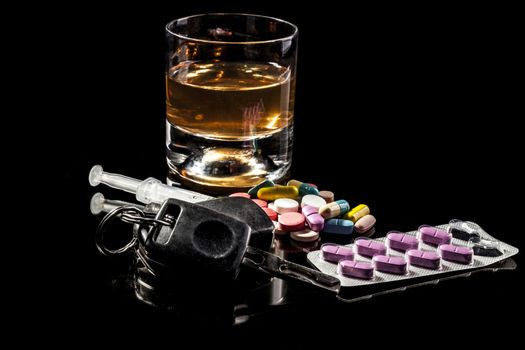 Alchohol,pills and car keys isolated on black background with reflection