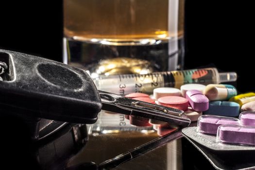 Car keys and pills isolated on black background with reflection