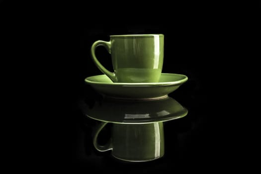 Green cup isolated on black background with reflexion