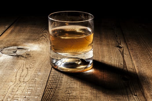 Glass of alcohol on wood table with shadow