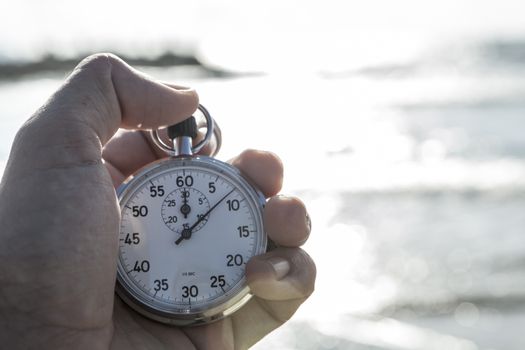 analog Stopwatch in hand with sea in the background