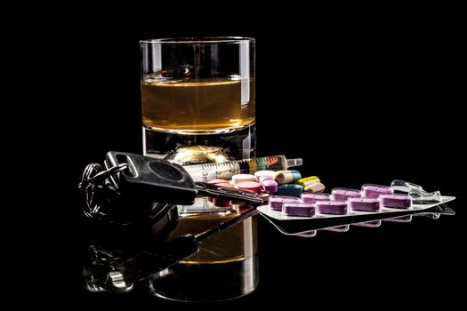 Alcohol, pills and car keys isolated on black background with reflection