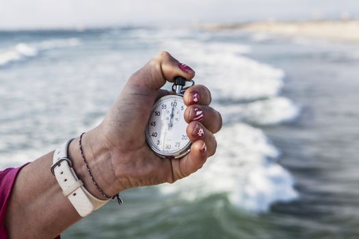 analog Stopwatch in hand with sea in the background