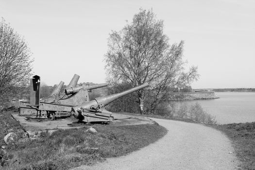 Four rusty cannons from the Russian period point out over the water from Suomenlinna sea fortress - monochrome processing