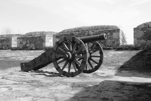 Old military cannon mounted on wheels, displayed in a bastion on sea fortress Suomenlinna, Helsinki - monochrome processing