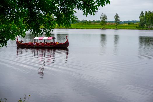 Tourist boat in the style of viking on river Daugava, Latvia. Ancient boat in Daugava river at Koknese. Old wooden viking boat in river Daugava, Latvia.