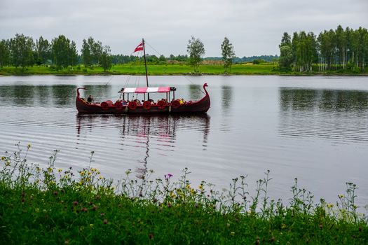 Tourist boat in the style of viking on river Daugava, Latvia. Ancient boat in Daugava river at Koknese. Old wooden viking boat in river Daugava, Latvia.
