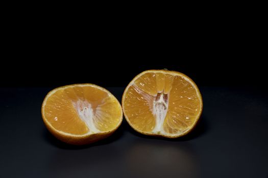 orange raw freh healthy food cut in two cut pieces on black background 