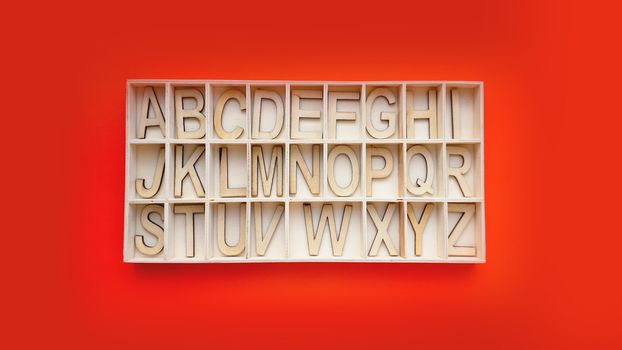 Wooden alphabet blocks with letters - box on a red background. Concept of learning english