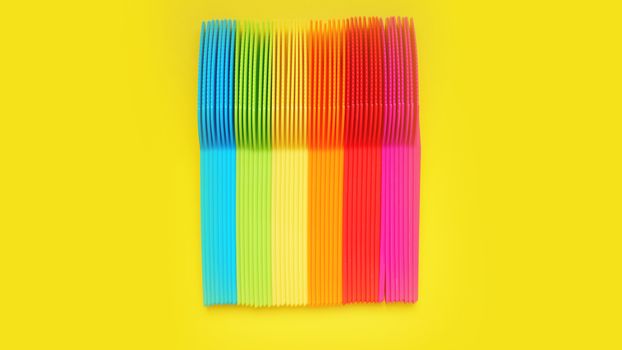 Plastic knives violet, orange, yellow, blue, red isolated on yellow background - bright summer concept for design and banners