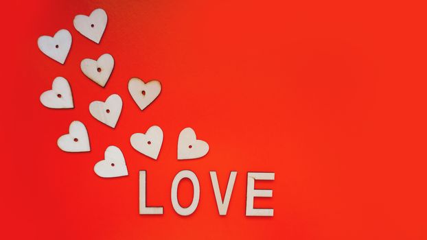 Valentines Day background with red hearts and letters love - made of wood on a red background. Top view. For banner or card