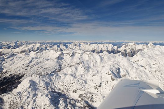 Flying above Mount Triglav in Julian Alps in winter, aerial landscape panorama of mountains covered with snow, highest mountain in Slovenia, Austrian Alps in background