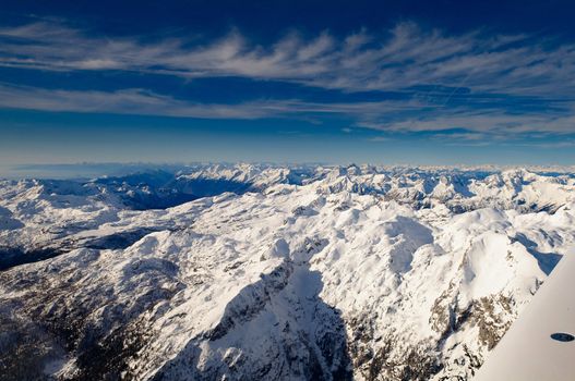 Flying above Mount Triglav in Julian Alps in winter, aerial landscape panorama of mountains covered with snow, highest mountain in Slovenia, Austrian Alps in background