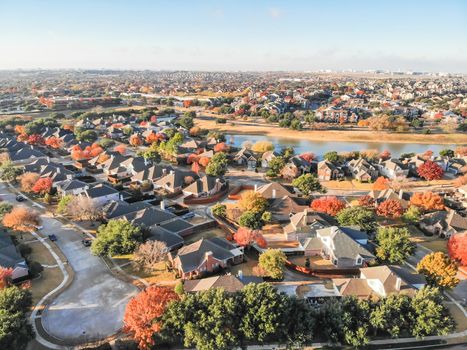 Aerial view waterfront residential subdivision with cul-de-sac dead-end street in suburban Dallas, Texas. Urban sprawl with row of single-family houses and colorful fall leaves, blue sky