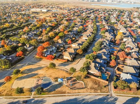 Top view community playground near residential area with row of single-family detached house and colorful autumn leaves. Urban sprawl subdivision in background