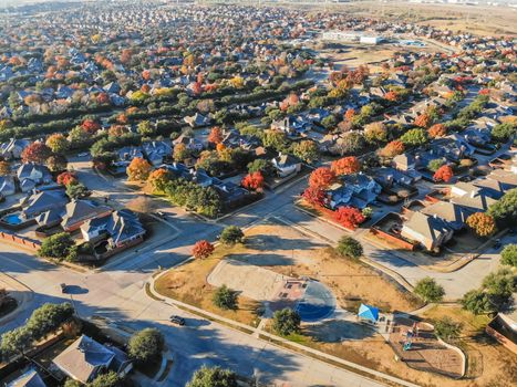 Top view community playground near residential area with row of single-family detached house and colorful autumn leaves. Urban sprawl subdivision in background