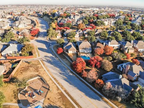 Top view community playground near residential area with row of single-family detached house and colorful autumn leaves. Urban sprawl subdivision in background