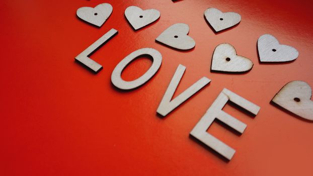 Valentines Day background with red hearts and letters love - made of wood on a red background. Top view. For banner or card