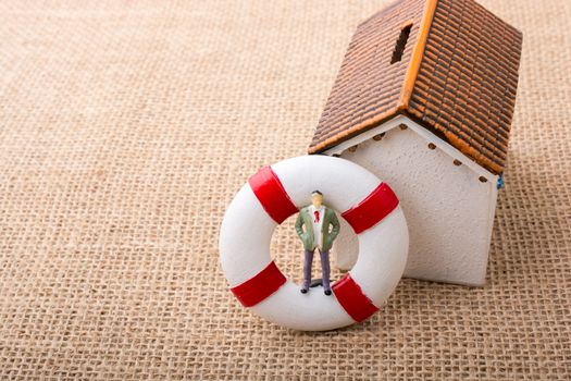 Model house and a life preserver with a man figure on it