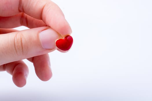 Red color heart shape earring in hand on white