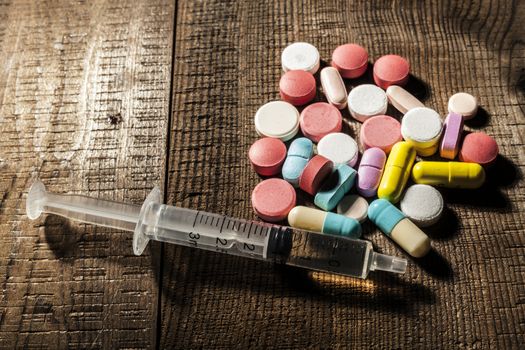 Pills and syringe on table with shadow