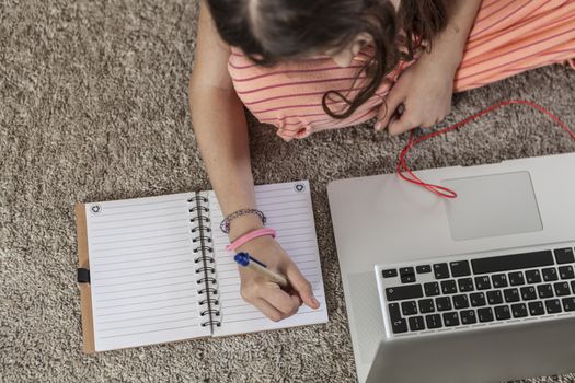 Kid writting something and a laptop near