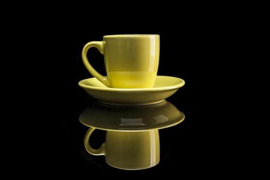 Yellow cup isolated on black background with reflexion