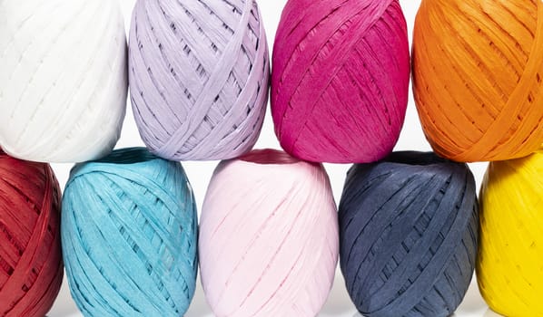 some balls of colored raffia on a white surface