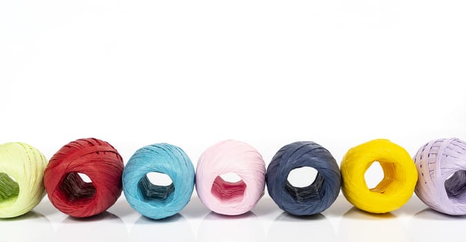 some balls of colored raffia on a white surface