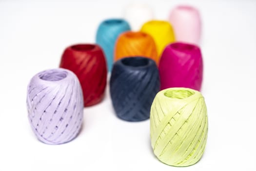 some balls of colored raffia on a white surface