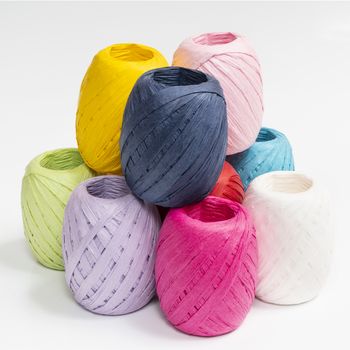 some balls of colored raffia on a white surface