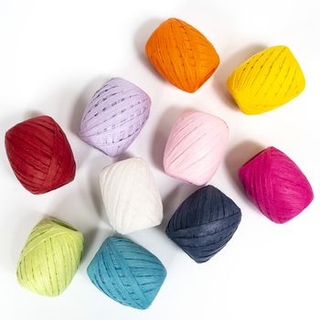 some balls of colored raffia on a white surface