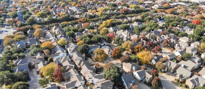 Panorama aerial drone view urban sprawl in suburban Dallas, Texas during fall season with colorful leaves. Flyover subdivision with row of single-family detached houses and apartment complex