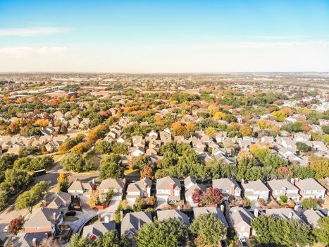 Top view residential subdivision in fall season with colorful autumn leaves near Dallas, Texas. Urban sprawl of residential houses and apartment building complex, blue sky