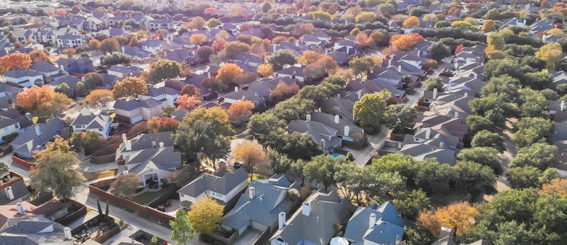 Panorama aerial drone view urban sprawl in suburban Dallas, Texas during fall season with colorful leaves. Flyover subdivision with row of single-family detached houses and apartment complex