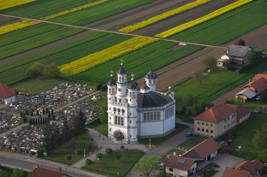 Aerial view of Holy Trinity Church in a small European village in sunset, a cemetery next to the church, unique architecture, Odranci, Slovenia, religious concept