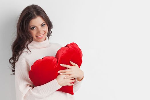 Beautiful woman in warm sweater with a big red heart shape pillow , copy space for text , Valentines day concept