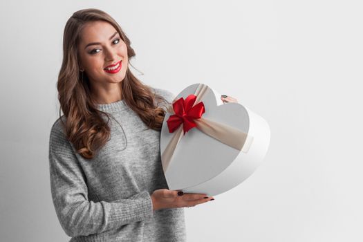 Beautiful young smiling woman holding decorated heart shaped box Valentines day concept