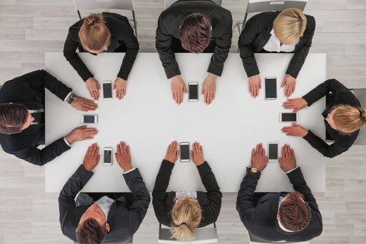 Business people not using smartphones sitting around white table