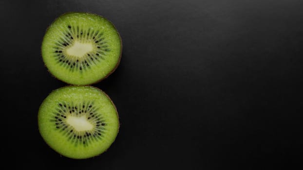 Juicy green kiwi fruit on a black background, top view, copy space