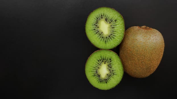 Juicy green kiwi fruit on a black background, top view, copy space