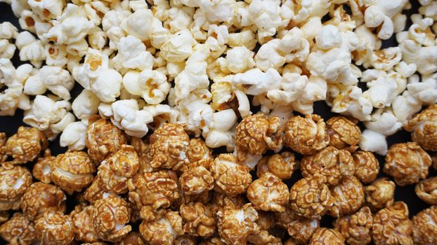 Assorted popcorn set background. Sweet and salty popcorn on black background. Still life, top view, flat lay. Concept cinema and entertainment