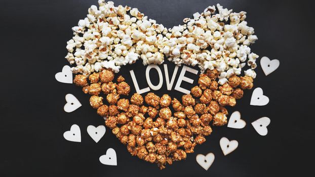 Love Cinema concept of popcorn arranged in a heart shape. Assorted popcorn set background. Sweet and salty popcorn on black background.