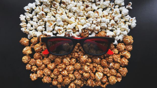 Abstract image of viewer, 3D glasses and popcorn on black background. Still life, top view, flat lay. Concept cinema and entertainment