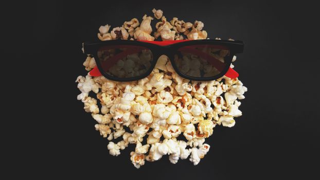 Abstract image of viewer, 3D glasses and popcorn on black background. Still life, top view, flat lay. Concept cinema and entertainment