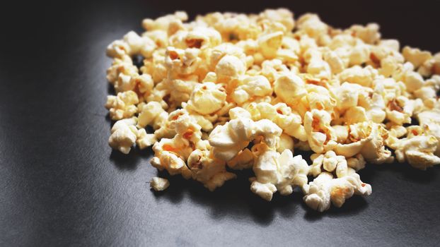 Heap of classic salty popcorn on black background. Concept cinema and entertainment